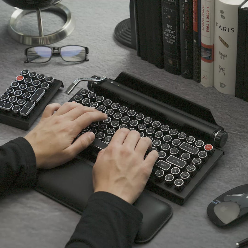 Video of a beautifully hand-assembled Qwerkywriter 2 in black and chrome connected to an iPad, demonstrating its working return bar and scroll knob.