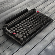 Qwerkywriter typewriter keyboard best in class premium all aluminum body in anniversary dark chrome left angle on grey wood grain background