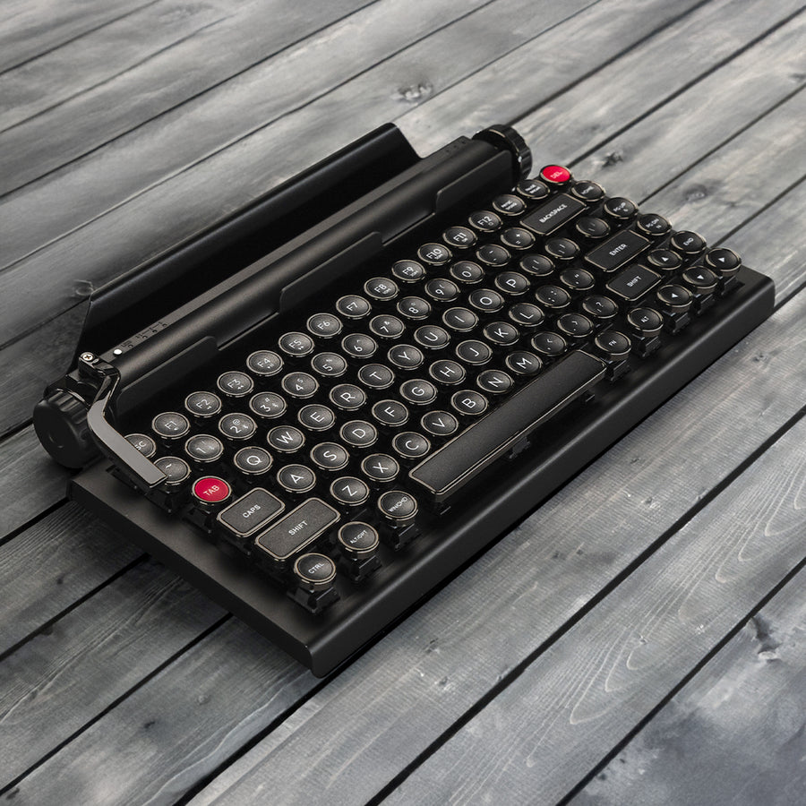 Qwerkywriter typewriter keyboard best in class premium all aluminum body in anniversary dark chrome left angle on grey wood grain background