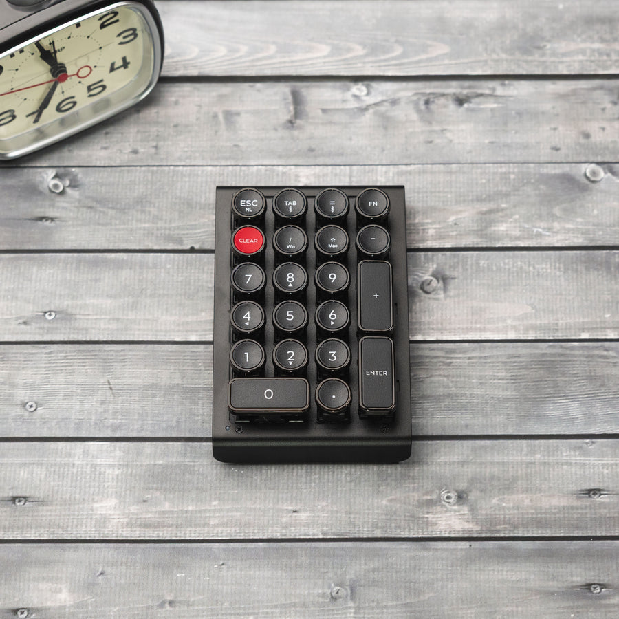 Qwerkywriter typewriter keyboard numkey numpad best in class premium all aluminum body in anniversary dark chrome front side view on dark wood grain with clock