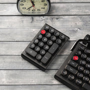 Qwerkywriter typewriter keyboard numkey numpad best in class premium all aluminum body in anniversary dark chrome right side view on dark wood grain with Qwerkywriter anniversary dark chrome typewriter keyboard and clock