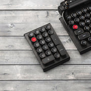 Qwerkywriter typewriter keyboard numkey numpad best in class premium all aluminum body in anniversary dark chrome left side view on dark wood grain with Qwerkywriter anniversary dark chrome typewriter keyboard