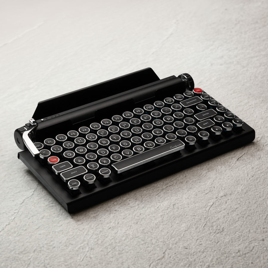 Qwerkywriter typewriter keyboard best in class premium all aluminum body in black chrome on grey wood grain background with hot swap tool and cherry mx blue switch hero image