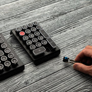 Qwerkywriter typewriter keyboard numkey numpad best in class premium all aluminum body in black chrome right view on grey wood grain with hot swap tool and cherry mx blue switch