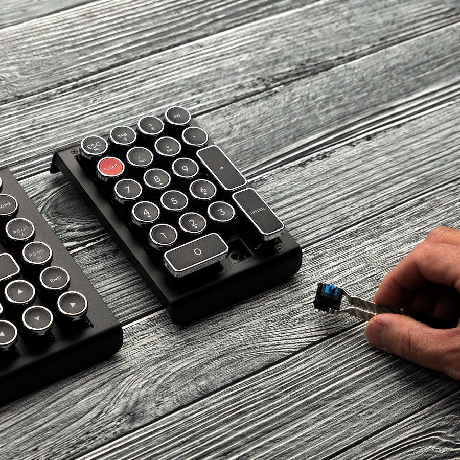 Qwerkywriter typewriter keyboard numkey numpad best in class premium all aluminum body in black chrome right view on grey wood grain with hot swap tool and cherry mx blue switch