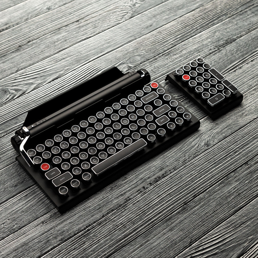 Qwerkywriter typewriter keyboard numkey numpad best in class premium all aluminum body in black chrome leftside view on grey wood grain with the qwerkywriter