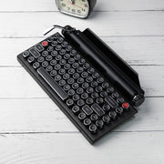 Qwerkywriter typewriter keyboard best in class premium all aluminum body in black chrome with a clock on white wood background US ANSI layout