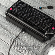 Qwerkywriter typewriter keyboard best in class premium all aluminum body in black chrome on grey wood grain background usb-c connection and charging cable
