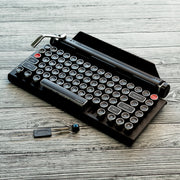 Qwerkywriter typewriter keyboard best in class premium all aluminum body in black chrome hero image on grey wood grain background and hot swap tool cherry mx blue switch