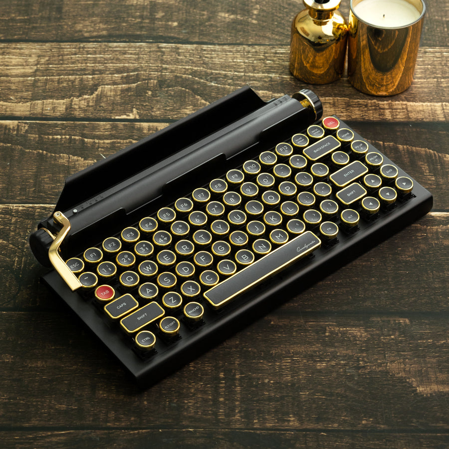 Qwerkywriter typewriter keyboard best in class premium all aluminum body in black gold hero image on brown wood grain background Alternate Angle
