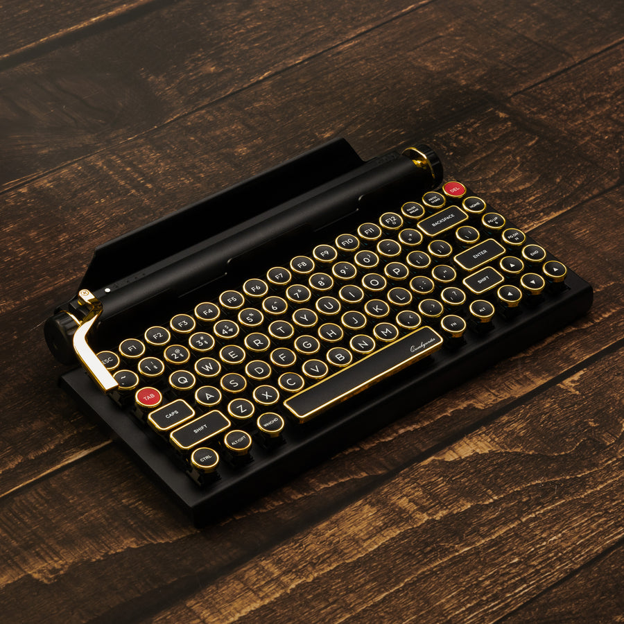 Qwerkywriter typewriter keyboard best in class premium all aluminum body in black gold hero image on brown wood grain background Alternate Angle