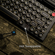 Qwerkywriter typewriter keyboard best in class premium all aluminum body in black gold close up view of hot swappable switches on brown wood grain background