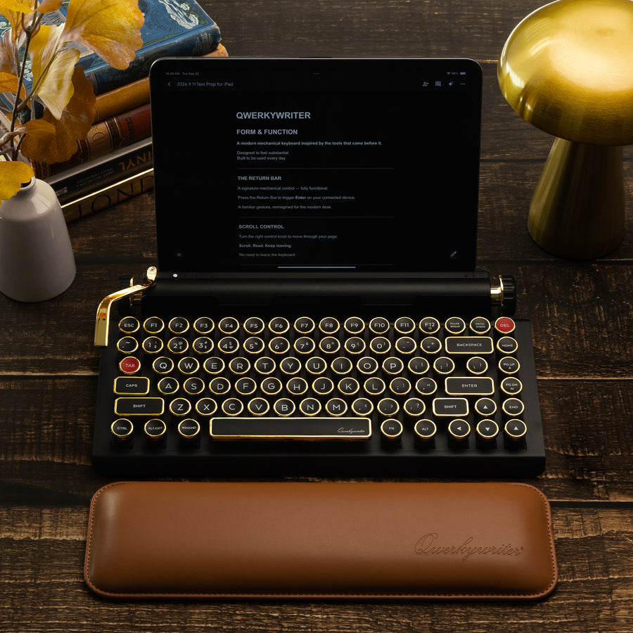 Qwerkywriter typewriter keyboard best in class premium all aluminum body in black gold top view of Ipad tablet on brown wood grain background