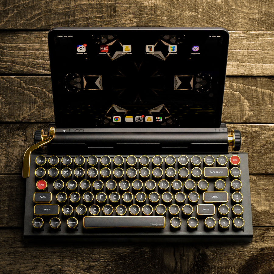 Qwerkywriter typewriter keyboard best in class premium all aluminum body in black gold top view of Ipad tablet on brown wood grain background