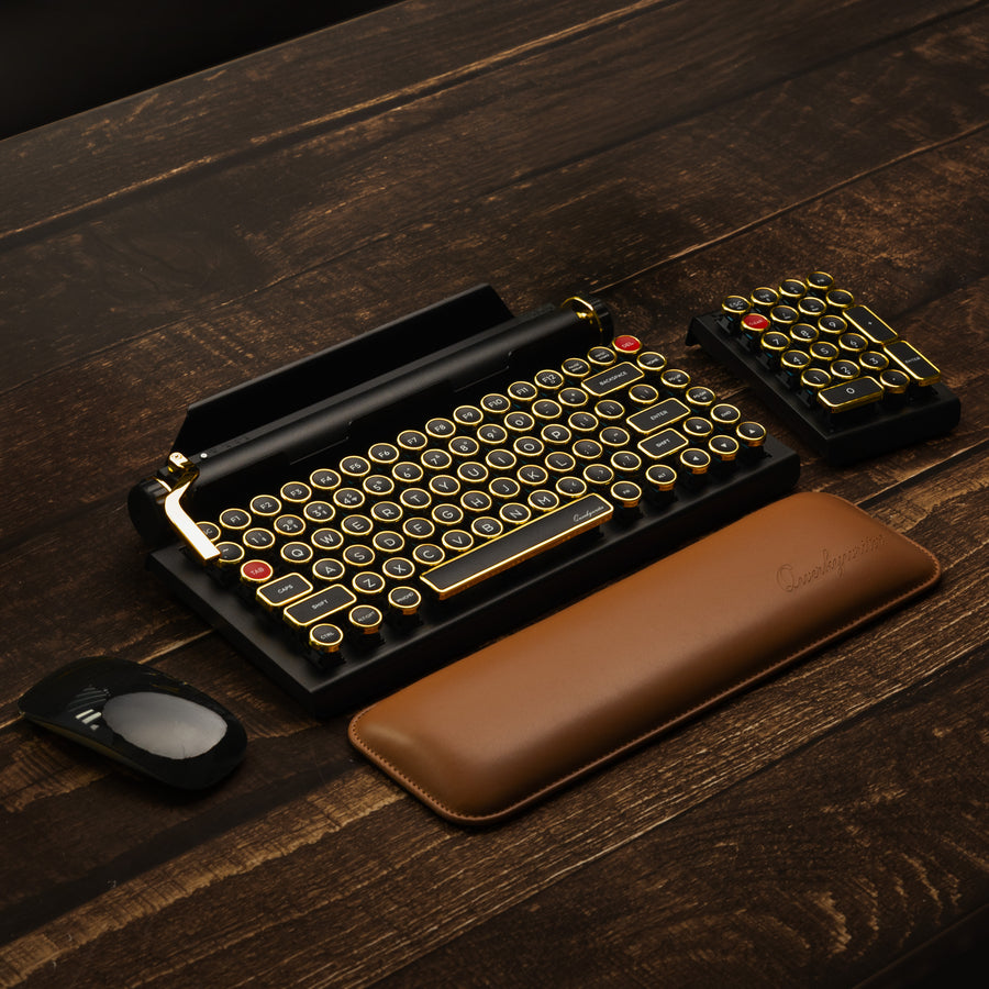 Qwerkywriter typewriter keyboard best in class premium all aluminum body in black gold hero image on brown wood grain background inside a library
