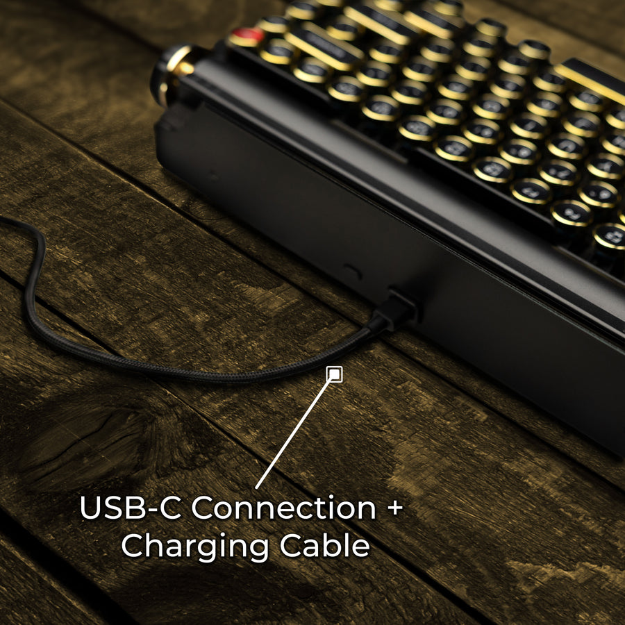 Qwerkywriter typewriter keyboard best in class premium all aluminum body in black gold close up rear back view of USB-C connection and charging cable on brown wood grain background