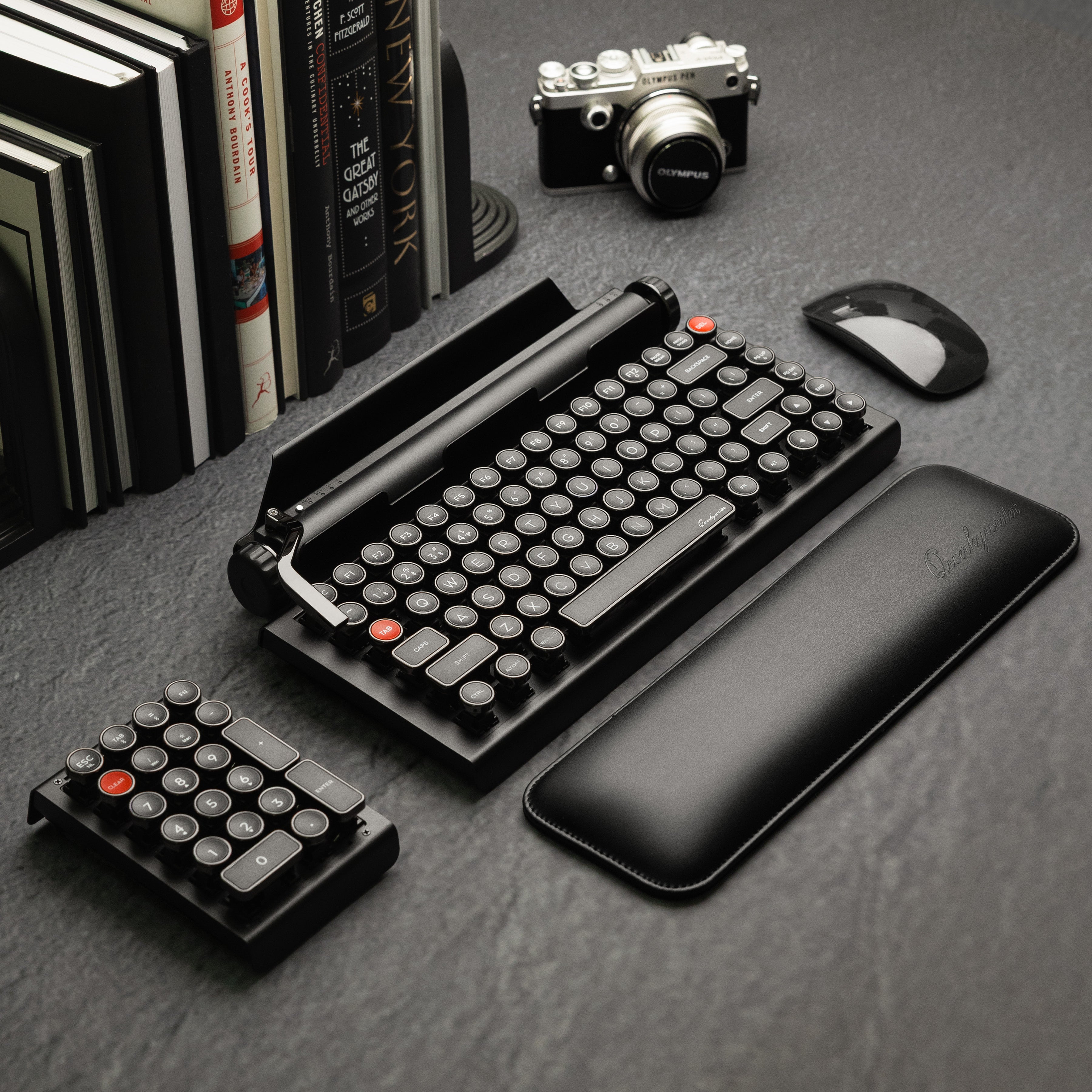 Qwerkywriter typewriter keyboard best in class premium all aluminum body in dark chrome hero image on grey stone slab background on a desk