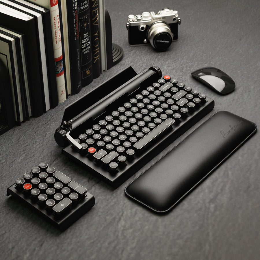 Qwerkywriter typewriter keyboard best in class premium all aluminum body in dark chrome hero image on grey stone slab background on a desk