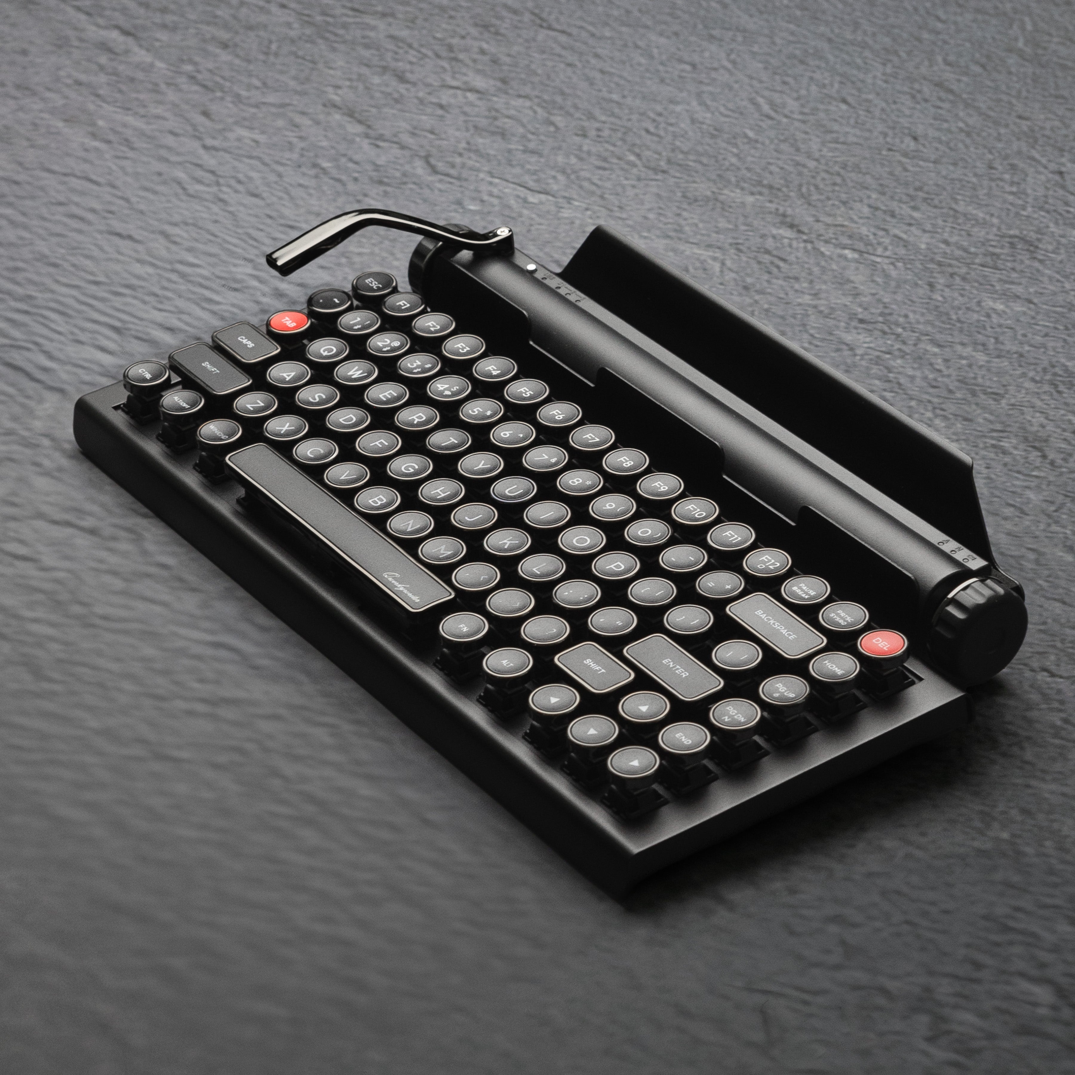 Qwerkywriter typewriter keyboard best in class premium all aluminum body in dark chrome hero image on grey stone slab background Alternate Angle