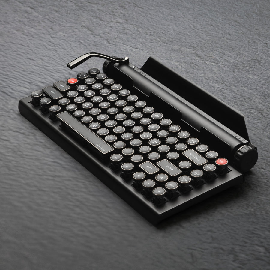Qwerkywriter typewriter keyboard best in class premium all aluminum body in dark chrome hero image on grey stone slab background Alternate Angle
