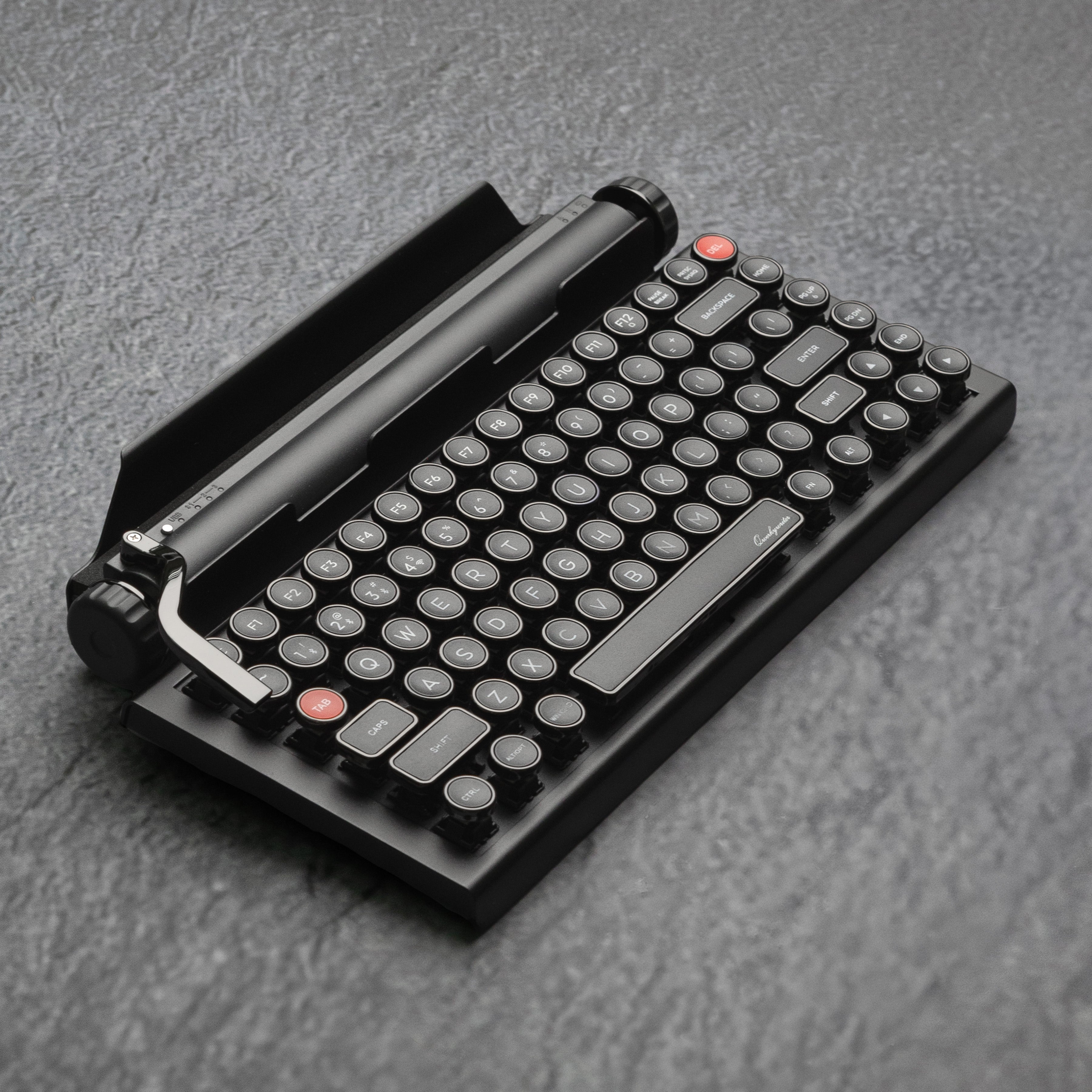 Qwerkywriter typewriter keyboard best in class premium all aluminum body in dark chrome hero image on grey stone slab background