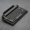 Qwerkywriter typewriter keyboard best in class premium all aluminum body in dark chrome hero image on grey stone slab background