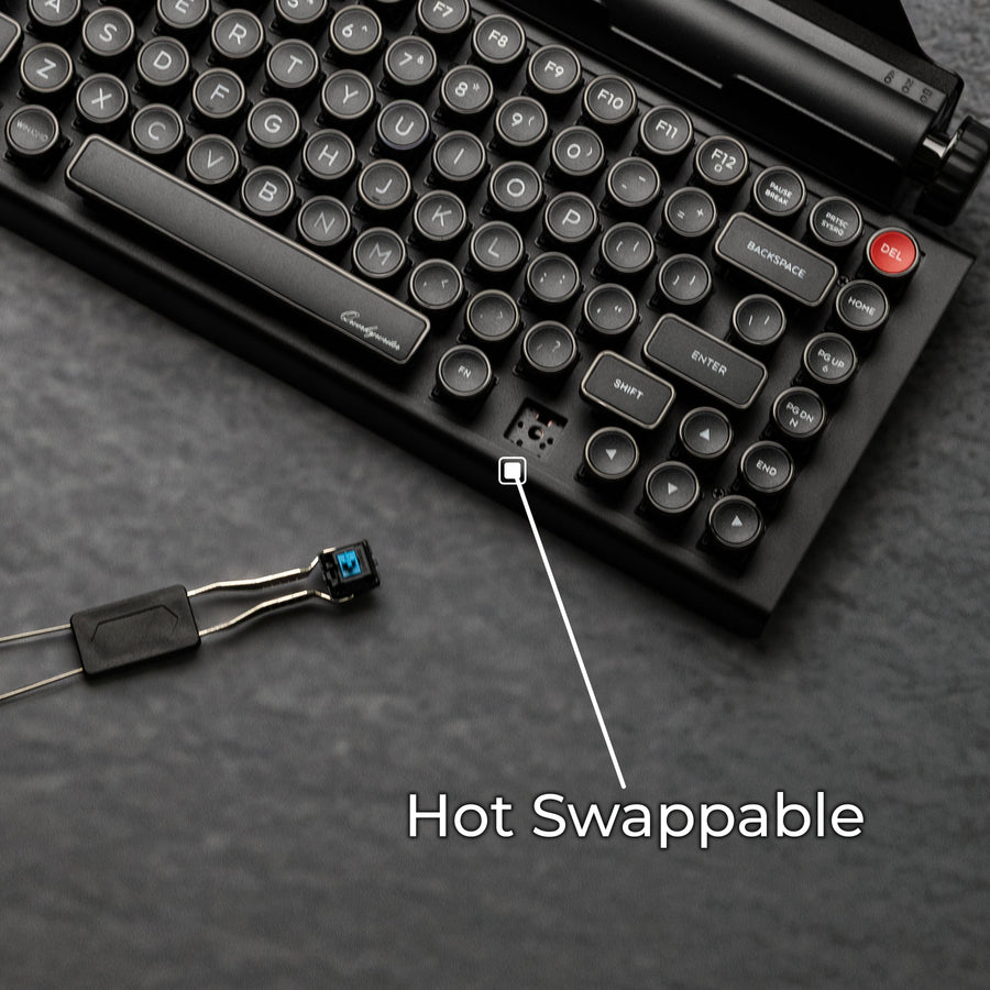 Qwerkywriter typewriter keyboard best in class premium all aluminum body in dark chrome close up view of hot swappable switches on grey stone slab background