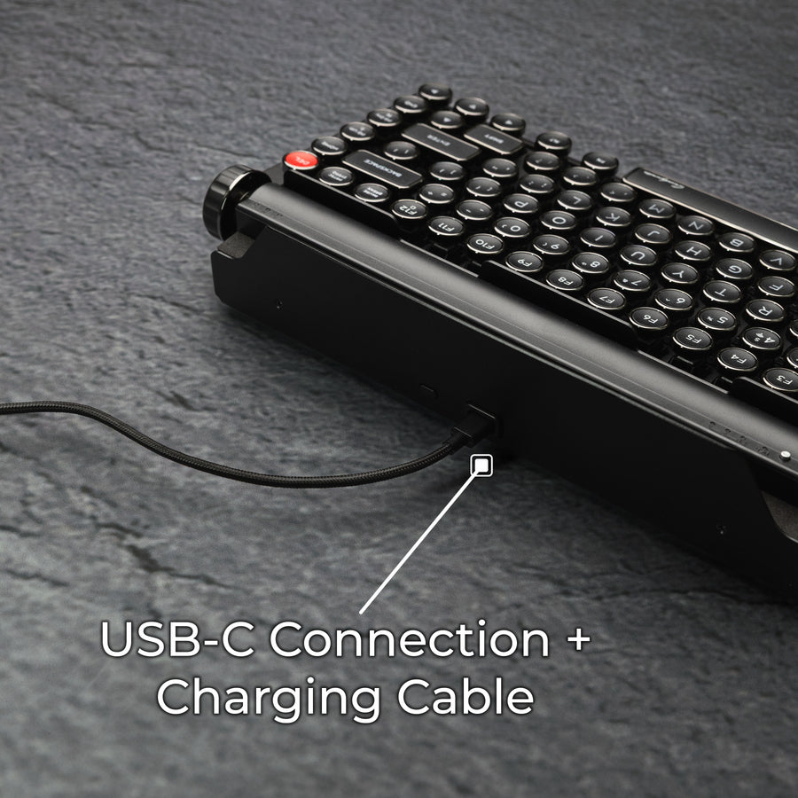 Qwerkywriter typewriter keyboard best in class premium all aluminum body in dark chrome close up rear back view of USB-C connection and charging cable on grey stone slab background