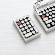 Qwerkywriter typewriter keyboard numkey numpad best in class premium all aluminum body in white chrome left side view on white wood grain with Qwerkywriter white chrome typewriter keyboard