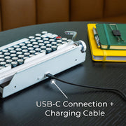 Qwerkywriter typewriter keyboard best in class premium all aluminum body in white chrome on dark wood background with USB C charging and connection cable with dongle