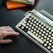 Qwerkywriter typewriter keyboard best in class premium all aluminum body in white gold on dark wood background person clicking cherry blue mx mechanical switch