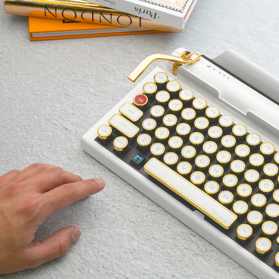 Qwerkywriter typewriter keyboard best in class premium all aluminum body in white gold on light background person clicking cherry blue mx mechanical switch
