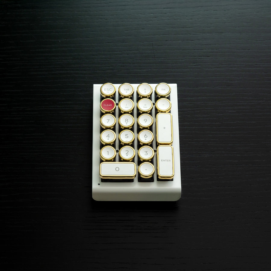 Qwerkywriter typewriter keyboard numkey numpad best in class premium all aluminum body in white gold front view on black wood grain 