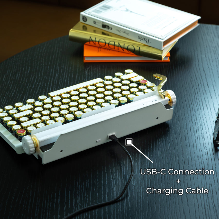Qwerkywriter typewriter keyboard best in class premium all aluminum body in white gold on dark wood background with USB C charging and connection cable with dongle